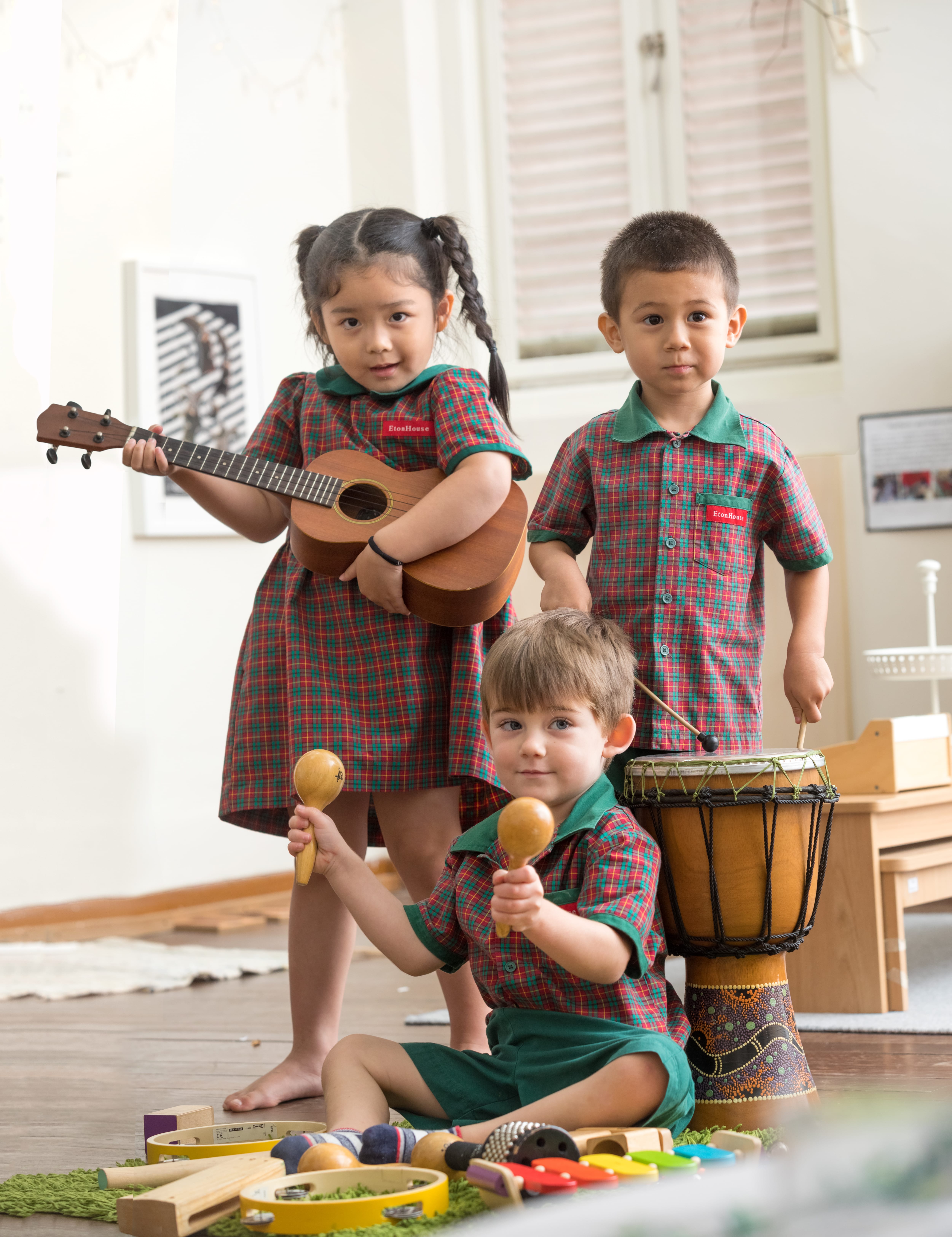 Three students of EtonHouse Nature Pre-School playing music intruments