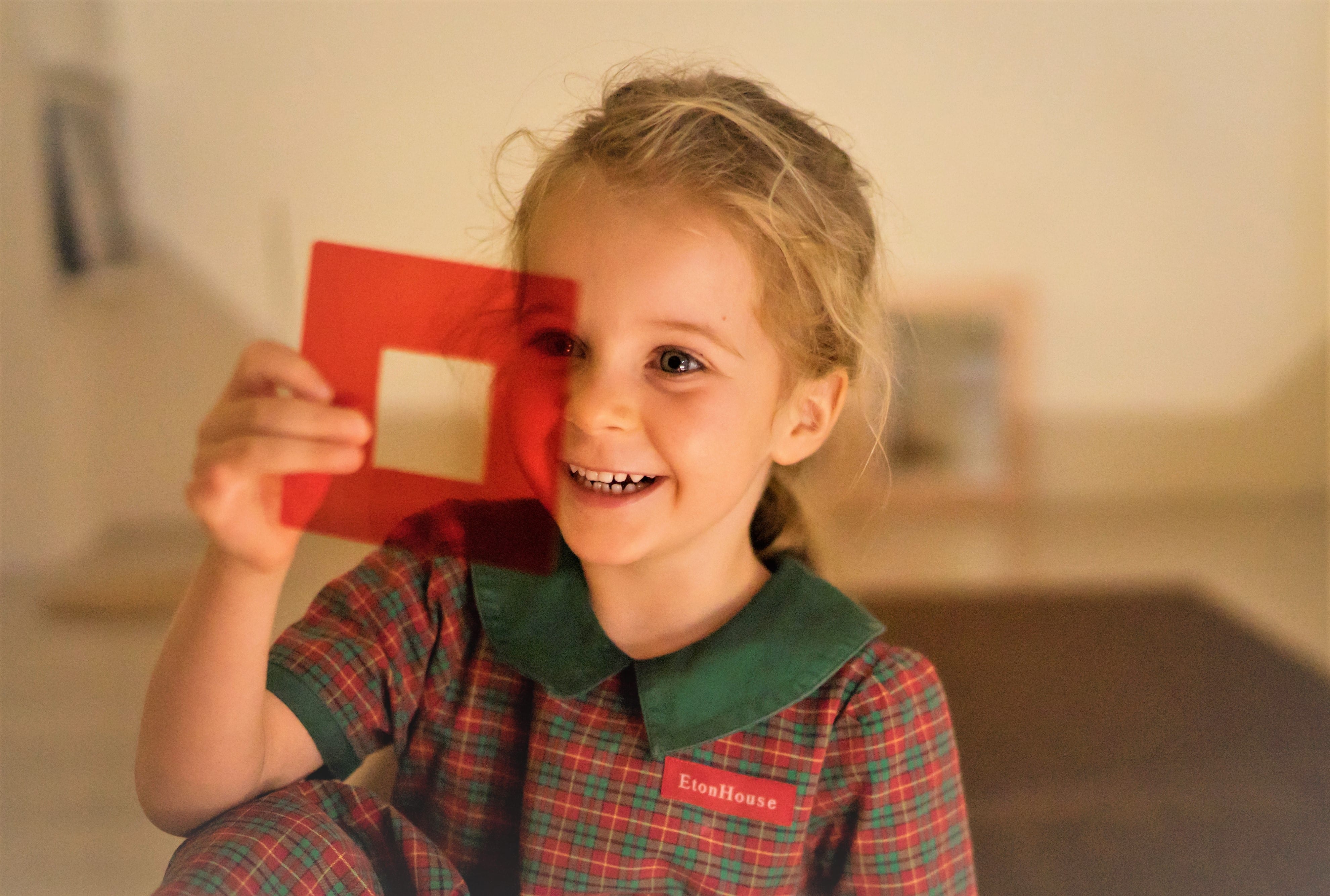 Student holding a red transparent square-shaped piece of cellophane