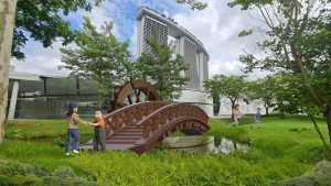 Children beside a wooden bridge surrounded by lush greenery