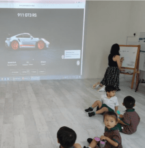 Teacher teaching students how to draw a car using an example