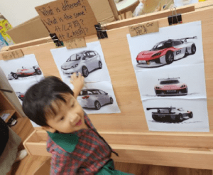 Young boy excitedly pointing out a picture of a car
