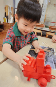 Child playing with a red car made from legos