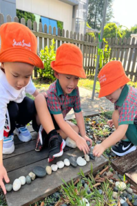 A group of kids lining up pebbles outdoors