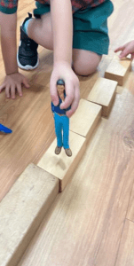 Kids playing with a figurine and wooden blocks