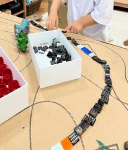Student creating a track using various paper cutouts
