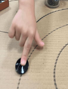 Student pushing a stone across a traced track