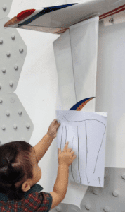 Student using a model plane as reference for his drawing