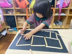 Student using popsicle sticks to create a building outline