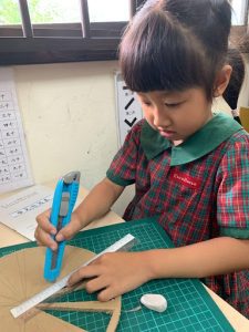 Student using a penknife to cut out cardboard shapes