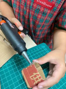Student using a glue gun on a carboard cylinder
