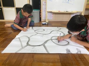 Two students sketching a map on large piece of paper