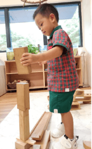 Little boy carefully stacking wood blocks