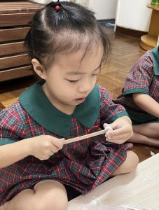 Little girl using a popsicle stick to create art