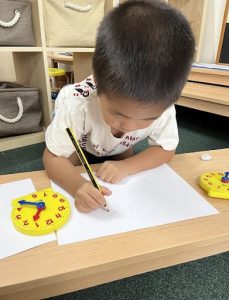 Child drawing a clock by using a toy for reference