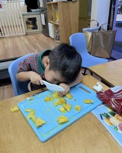 Child carefully cutting some fruit on a chopping board