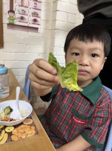 Young boy proudly showing off a piece of lettuce